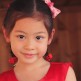 Girl with red dress and red bow giving beautiful smile to the camera