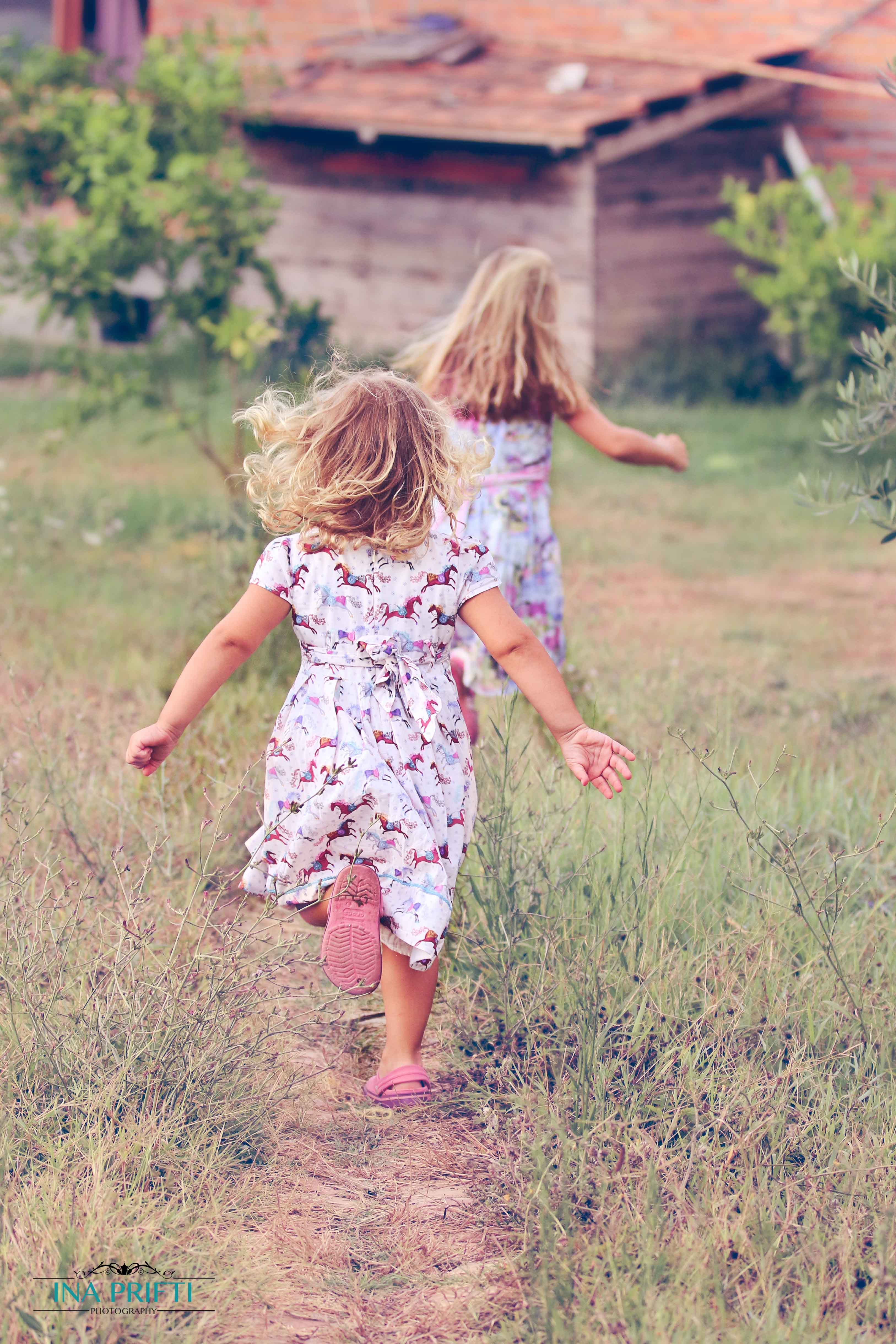 Beautiful picture of two girls running through field towards an old house